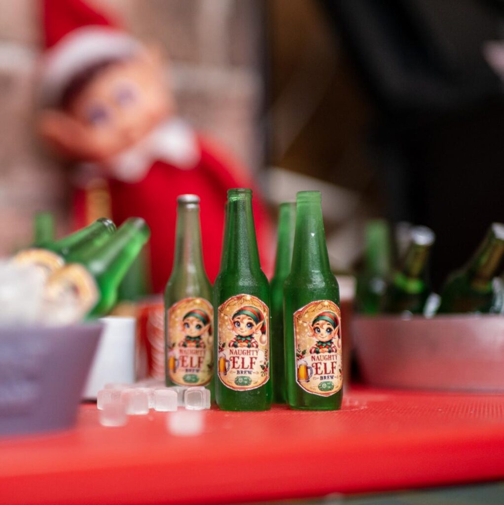 An elf with a table of Naughty Elf Brew bottles