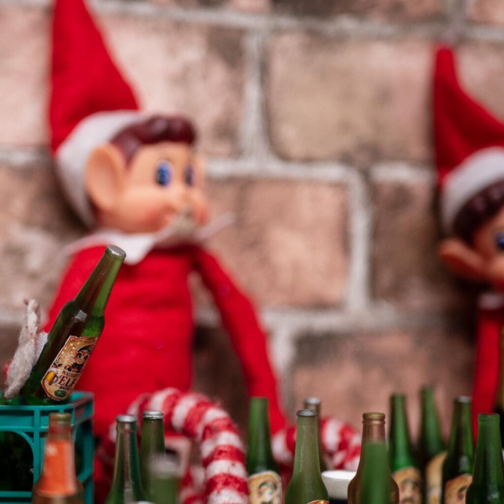 An elf holding a Naughty Elf Brew bottle
